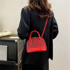 Gros plan d'un sac à main rouge en forme de coquille avec bandoulière sur veste noire