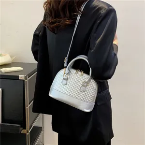Détail du sac coquille argenté avec texture d'écailles métalliques et zip doré