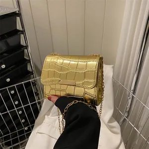 Detail of metallic gold crocodile embossed mini square bag with gold chain strap