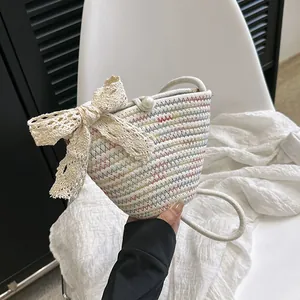 Détail d'un sac seau tressé orné d'un nœud en dentelle blanche et bouton en perle
