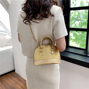 Détail du sac coquille doré champagne avec texture matelassée en diamant et finition métallique