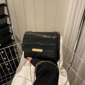 Detailed view of black crocodile pattern faux leather bag with gold chain and buckle