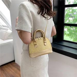 Détail du sac à main doré texturé avec design tressé et base en cuir synthétique