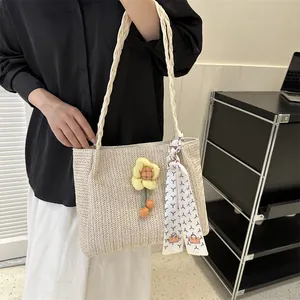 Vue détaillée du sac cabas beige tressé avec pendentif floral et foulard en soie à motifs