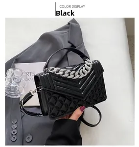 Détail d'un sac à main noir brillant avec surpiqûres en V et cuir matelassé