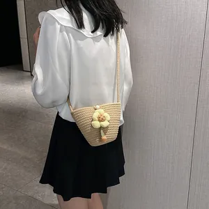 Side view of a woven straw bucket bag with large yellow flower and pearl button detail