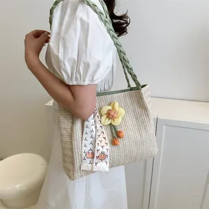 Sac fourre-tout tissé beige avec anses vertes et breloque florale pour un look d'été