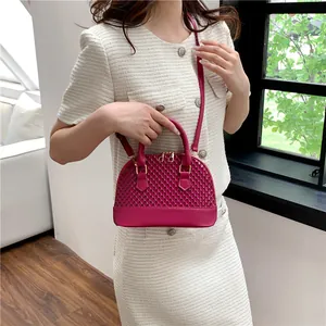 Sac à main en forme de coquillage magenta porté en bandoulière pour un style chic