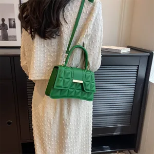 Detailed view of green quilted handbag with geometric patterns and gold metal buckle