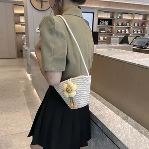 Detail of woven bucket bag with yellow floral charm worn by a model in a bookstore