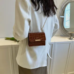 Brown crocodile pattern crossbody bag with a gold chain strap and glossy finish