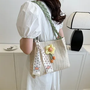 Vue détaillée du sac cabas en paille avec anse tressée verte et décoration florale