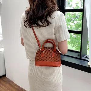 Détail du sac coquillage marron tissé avec bandoulière réglable et ferrures dorées