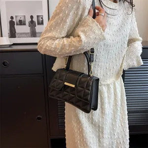 Close-up of black quilted shoulder bag with elegant gold metal bar and textured leather