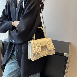 Detail of cream quilted leather handbag with gold metal clasp and top handle