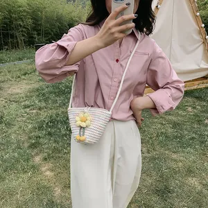 Chic hand-woven bucket bag with yellow sunflower charms, styled with pink shirt and white pants