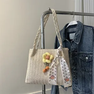 Détail du cabas en paille tressée avec breloque fleur jaune et foulard décoratif