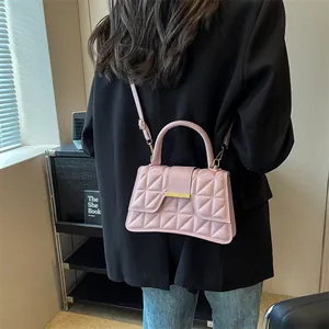 Pink quilted shoulder bag with gold clasp shown from back view on model's shoulder