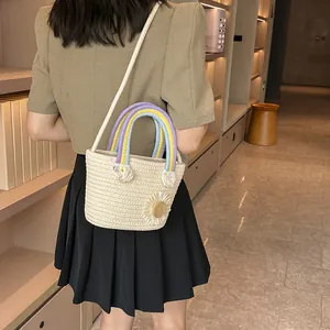 Détails des poignées arc-en-ciel et décor marguerite sur un sac seau tressé beige