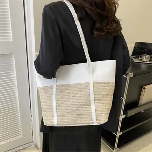 Detail einer weißen Leder-Stroh-Tragetasche, getragen als elegante Unterarm-Schultertasche