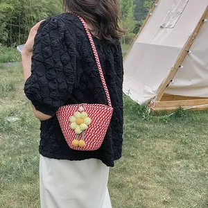 Red and white woven straw bucket bag with yellow floral charm for summer beach look