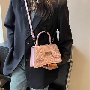 Detail of light pink quilted shoulder bag with gold metal trim worn by a fashion model