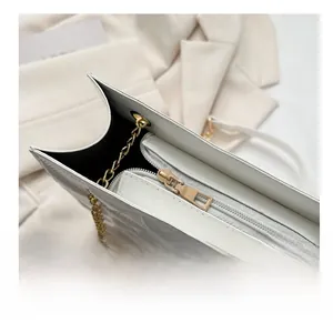 Détail de la fermeture éclair dorée et texture matelassée du sac blanc à bandoulière