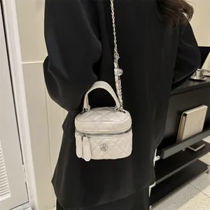 Dettaglio di una mini borsa trapuntata bianca con logo camelia e tracolla a catena
