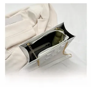 Vue intérieure du sac blanc matelassé contenant téléphone, portefeuille et parapluie