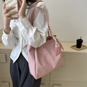 Detail of pink tote bag featuring a woven handle and decorative floral silk scarf