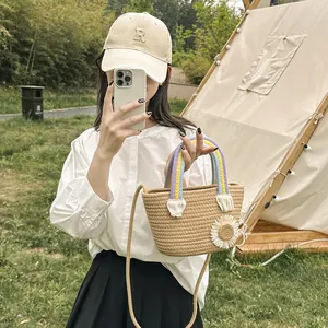 Détail du sac seau en paille tressée avec applique marguerite et poignée arc-en-ciel