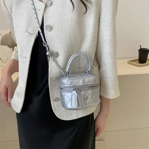 Dettaglio del vanity case trapuntato argento con ciondolo a fiore e tracolla