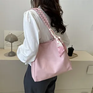Pink tote bag detail with braided shoulder strap and decorative floral silk scarf