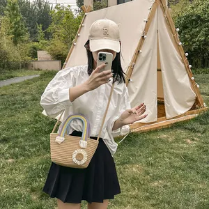 Sac seau en paille avec poignées arc-en-ciel et fleurs de marguerites en extérieur