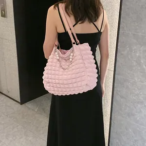 Detail of pink bubble texture tote bag featuring a decorative pearl and metal chain