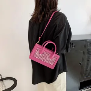 Detailed side view of a magenta handbag with sparkling rhinestones and a crossbody strap