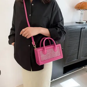 Close-up of pink rhinestone crossbody bag on a model in a modern interior setting