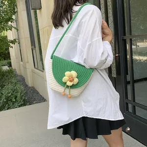 Detail of hand-woven straw bucket bag featuring a yellow flower and green strap accents