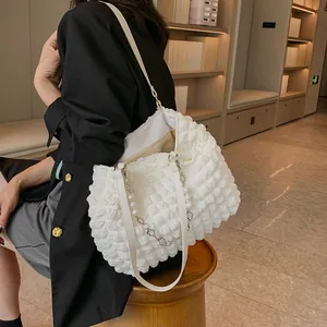 Close-up of white bubble texture tote bag with elegant pearl and floral chain details