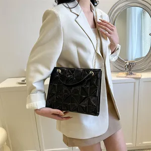 Détail de la texture géométrique 3D noire et de la chaîne dorée du sac à bandoulière