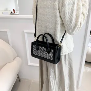 Detail of elegant black handbag with shimmering silver rhinestones and gold hardware