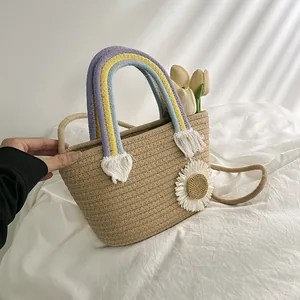 Détail du sac seau tissé main avec poignée arc-en-ciel et ornement de marguerite blanche