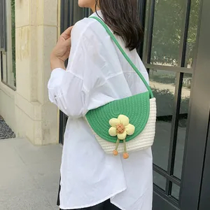 Detail of green straw bucket bag with floral accent and thin braided strap
