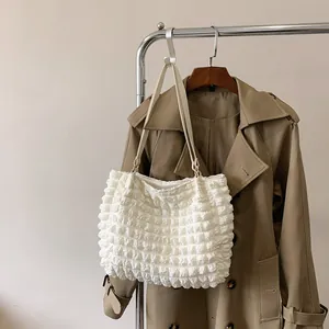 Detail of white large capacity tote bag featuring bubble pleated texture fabric and straps
