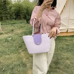 Detail of hand-woven purple straw tote bag with a golden round buckle closure