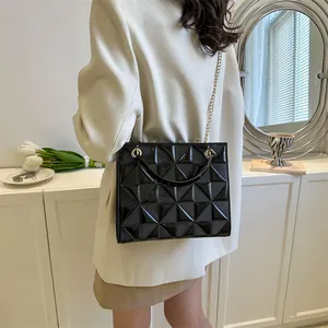 Détail du sac noir verni à texture géométrique avec bandoulière en chaîne dorée chic