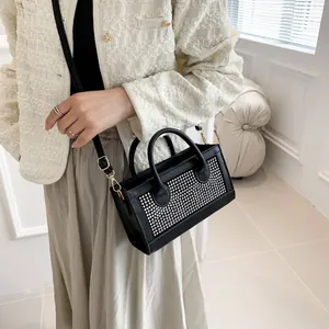 Detailed view of a black crossbody bag with silver rhinestones on a model's outfit