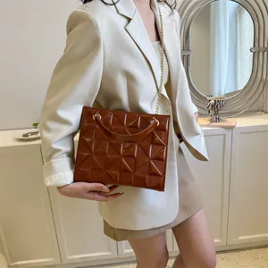 Détail d'un sac bandoulière matelassé marron foncé avec chaîne dorée et texture 3D