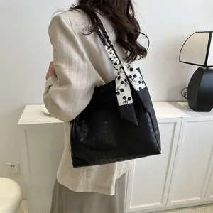 Large black textured leather tote bag with stylish printed scarf on shoulder strap
