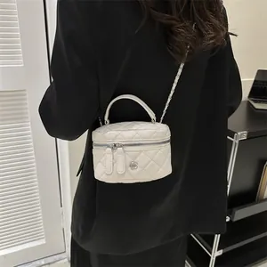 Mini borsa a scatola bianca trapuntata con catena e camelia indossata da modella